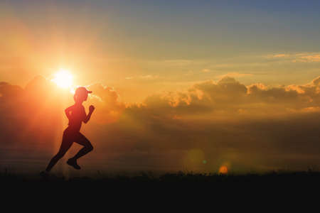 Woman running alone at beautiful sunset in the valley. Summer sport and healthy concept.の写真素材
