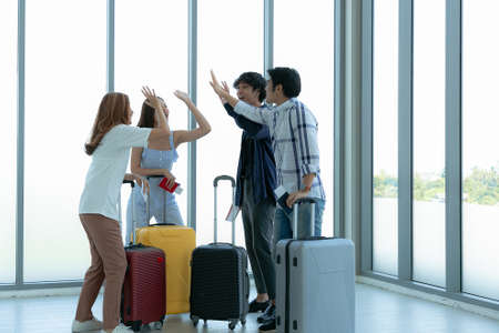 Asian young tourist friend group giving high-five during enjoy at airport terminal before journey.の写真素材