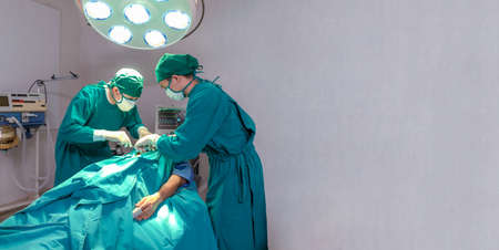 Professional intelligent surgeons standing near the patient and performing an operation. copy spaceの写真素材