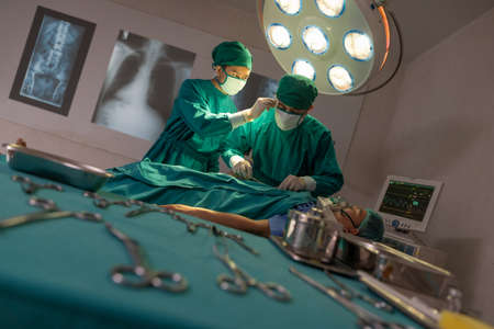 Professional intelligent surgeons standing near the patient and performing an operation. copy spaceの写真素材
