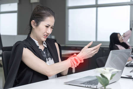 Two asian coworkers use laptop work together in office.