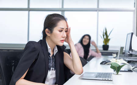 Two asian coworkers use laptop work together in office.の写真素材