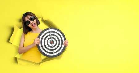 Portrait of shocked woman shopping bags with expression looking through torn hole in yellow paper. Banner, free copy empty space for advertising.の写真素材