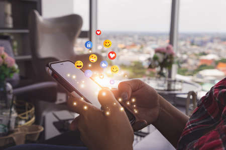 Young man using smartphone sending emojis. Mobile smartphone sending text messages emoji emoticon.の写真素材