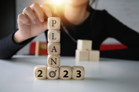 Hand holding wooden cubes change with plan on 2023, Development to success and motivation.