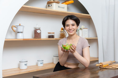 Portrait of a happy playful girl eating fresh salad from a bowl.の写真素材