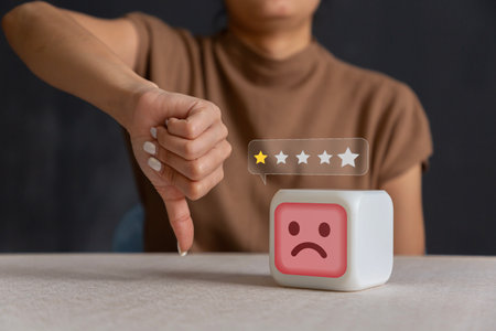 Portrait of female model pointing thumb down for negative, incorrect or displeased. Thumbs down and frowning in frustration,の写真素材