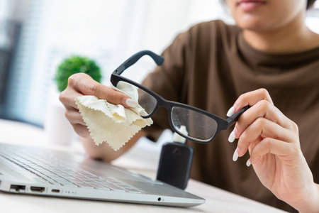 Women hand cleaning trendy black glasses lens with white cream microfiber tissue. healthcare, vision and medicine conceptの写真素材