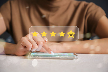 Close up of man hand pressing on smartphone screen with gold five star rating and press level...