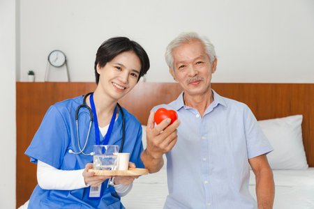 Young friendly asian female caregiver look at camera to happy senior man in nursing home.の写真素材