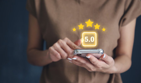Hand using smartphone with popup five star icon for feedback review satisfaction service or business satisfaction survey.の写真素材