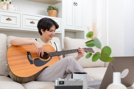 Playful asian woman playing acoustic guitar music instrument at home, young Asian musician girl lifestyleの写真素材