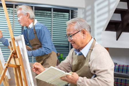 senior painting in art class with friends from her care home for the aged copying a painting with water colors in retirement home.の写真素材