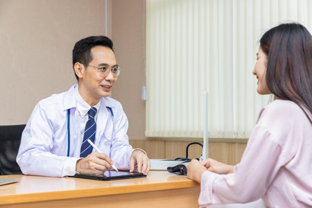 Asian doctor talking and explaining test result and diagnosis to demoralized patient in hospital.の写真素材
