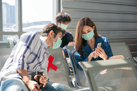 Happy Asian colleagues using smartphone checking flight or online check-in at airport togetherl, summer holiday or mobile phone.の写真素材