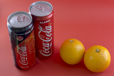 KAJANG, MALAYSIA - JANUARY 1, 2017: Closeup shot of Coca Cola Classic Tin Can and Coca Cola Zero on Red Background with Orange Lemonのeditorial素材