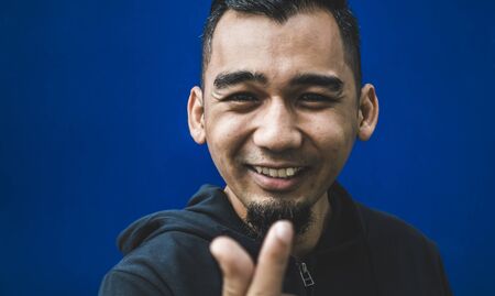 Closeup shot of happy young man showing love signの写真素材
