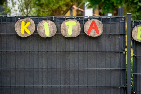 A black kindergarten fence with the abbreviation KITA in colorful letters on it.の写真素材