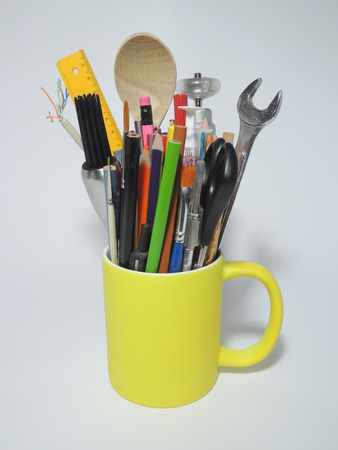 Coffee cup filled with color pencils, workshop tools, kitchen tools, brushes, etc. The image illustrates a multi-talented person or a innovative person spanning multiple disciplines indicated by the broad range of tools.の写真素材