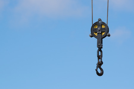 Vintage black crane hook isolated on blue sky with room for writing.