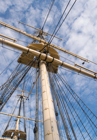 Wooden sail ship rigging against blue sky with clouds