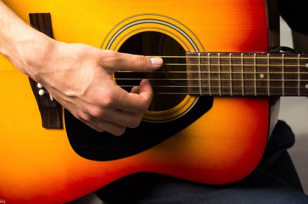 close up of a male hand playing acoustic guitarの写真素材