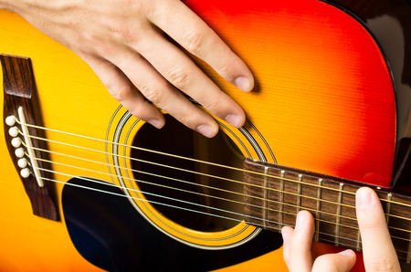 close up of a male hand playing acoustic guitarの写真素材
