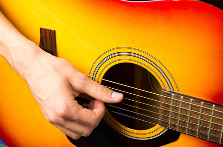 close up of a male hand playing acoustic guitarの写真素材