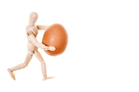 wooden dummy that carries with caution, a fragile fresh eggの写真素材