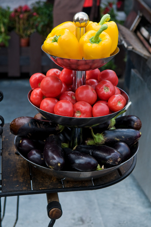 Bright fresh vegetables outsde a street restaurant in Moscow.Yellow peppers, red tomatoes, and purple eggplants are arranged on a tiered tray.の写真素材