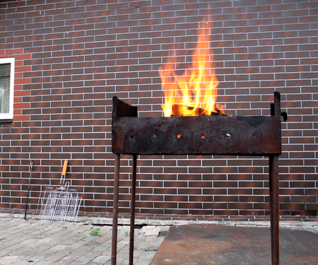 Firewood and fire in the old rusty charcoal grill on a brick wall backgroundの写真素材