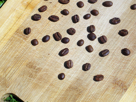Roasted coffee beans on the old wooden cutting board closeup, may be used as backgroundの写真素材
