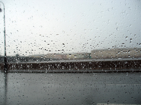 The cityscape behind the glass with rain drops during the rainstormの写真素材