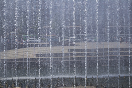 Summer cityscape with street and square in the distance trough the wall of water from the fountainsの写真素材