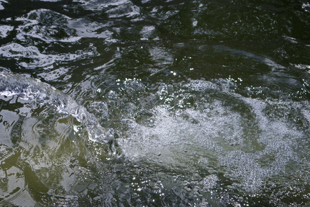 Boiling and foaming bubbled water falling down from the jet in a large fountain reservoirの写真素材