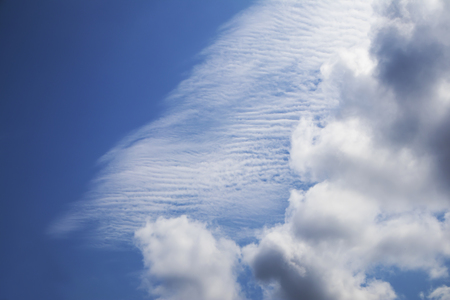 White cumulus and spindrift clouds against deep blue sky, bright beautiful atmospheric backgroundの写真素材