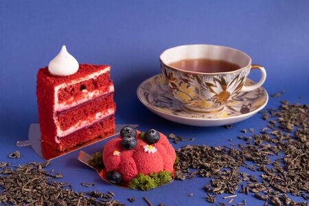 Two appetizing delicious red cakes and a cup of tea on a violet backgroundの写真素材