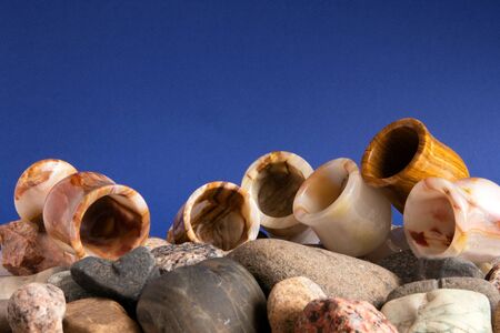 Still life with six onyx glasses lying on a pile of pebble against violet backgroundの写真素材
