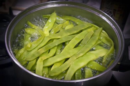 The top of large metal pan with boiling green bean pods insideの写真素材