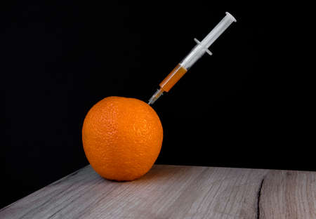 Bright orange on a wooden board and syringe inside it extracting orange liquidの写真素材
