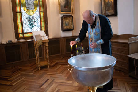 Saint-Petersburg, Russia, July 5, 2020. Priest in cassock makes preparations for christening in an...