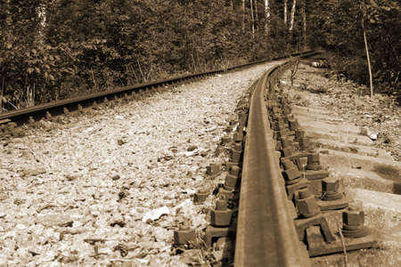 Old forest railway track with rusty rails going into the distance, sepia toneの写真素材