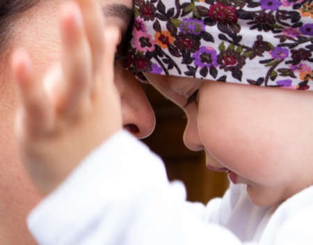 Little cute baby girl in her motherâs arms playing with her handsの写真素材
