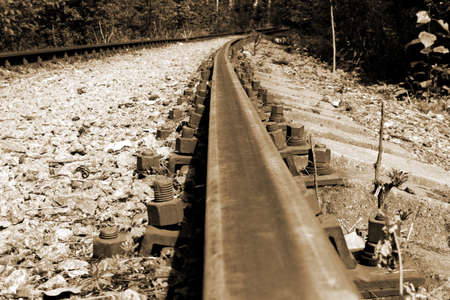 Old forest railway track with rusty rails going into the distance, sepia toneの写真素材