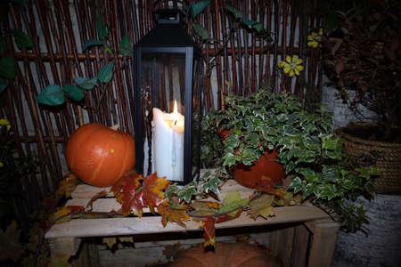 Street Halloween decoration with pumpkins, flower pots, rural fence and big candleの写真素材
