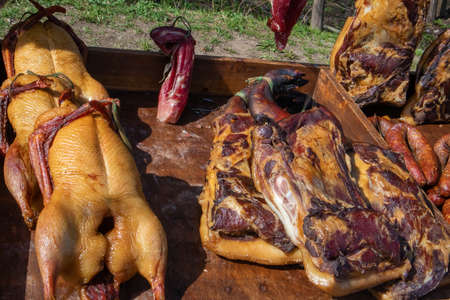 Few appetizing rustic homemade smoked meats, chicken and pork ham at the village fair trade tentの写真素材
