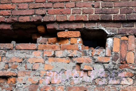 Old half destroyed stone wall of red bricks with big potholeの写真素材