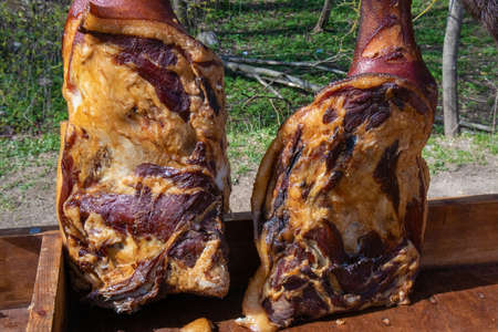 Two appetizing homemade smoked pork hams hanging on hooks at the village fair trade tentの写真素材