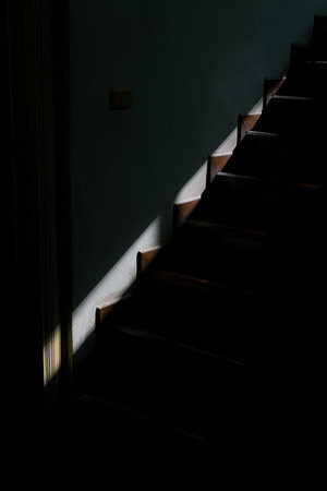 Staircase in the dark, illuminated by the sun and hard, strong shadowの写真素材