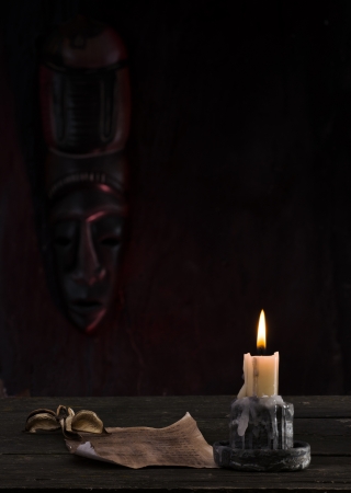 reading a letter by candlelight with an African maskの写真素材